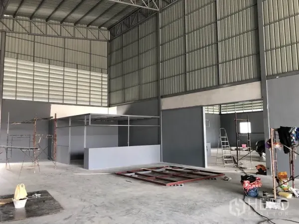 Warehouse for rent in Bang Khen, Nonthaburi - Interior showing partitioned office area, scaffolding and wide-span steel structure.