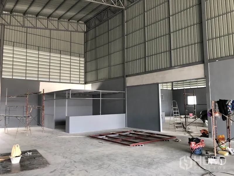 Warehouse for rent in Bang Khen, Nonthaburi - Interior showing partitioned office area, scaffolding and wide-span steel structure.