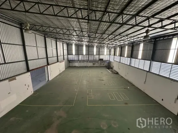 Warehouse for rent in Suan Luang, Bangkok - Aerial view of expansive high‑ceiling warehouse hall with insulated roof and marked floor.