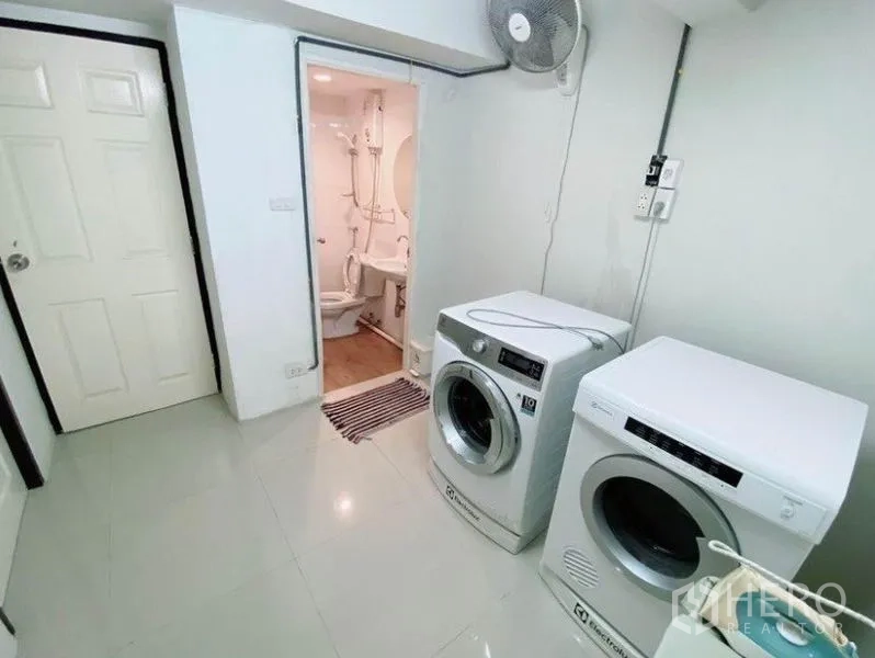 Townhouse for rent in Wang Thonglang, Bangkok - Laundry room with front-load washer and dryer next to a compact bathroom.