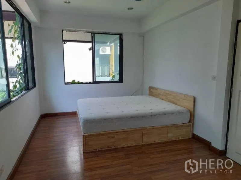 Detached House for rent in Prawet, Bangkok - Sunlit bedroom with wood flooring, big windows and a platform bed with storage drawers.