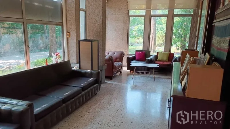 独立式住宅 出租在Phaya Thai, Bangkok - 明亮起居室，水磨石地面，多组沙发与通高窗户，面向绿色景致。