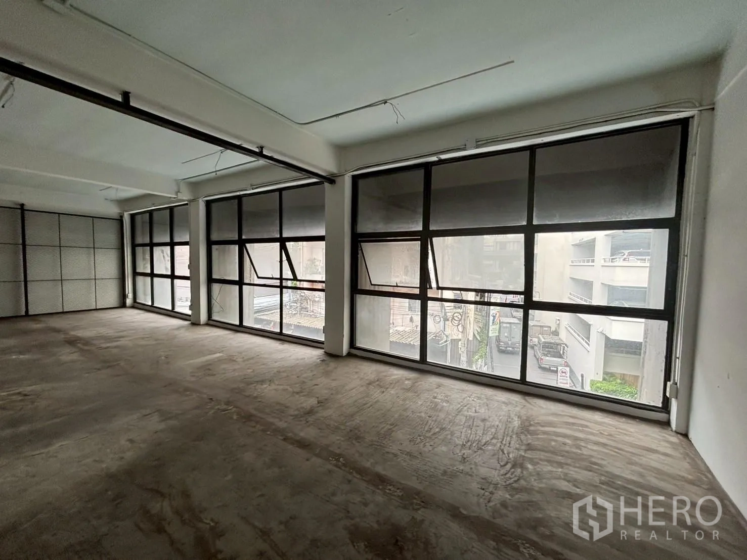 พื้นที่ขายปลีก ให้เช่า - ยูนิตแบบโอเพ่นแปลน พื้นคอนกรีต หน้าต่างกรอบอลูมิเนียมสีดำมองเห็นถนน ภายในสไตล์ลอฟต์