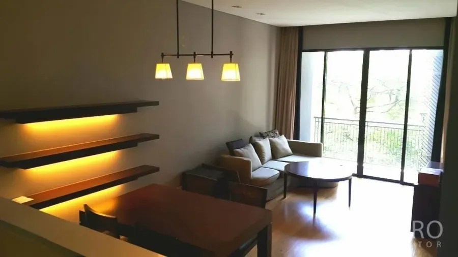 公寓 出售在Watthana, Bangkok - 客厅采光充足，落地窗与阳台望向绿景，配沙发与餐桌，墙面暖光灯，通罗区域现代公寓。