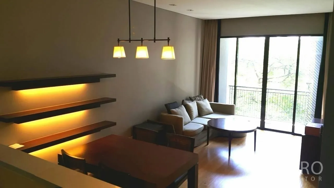 公寓 出售在Watthana, Bangkok - 客厅采光充足，落地窗与阳台望向绿景，配沙发与餐桌，墙面暖光灯，通罗区域现代公寓。