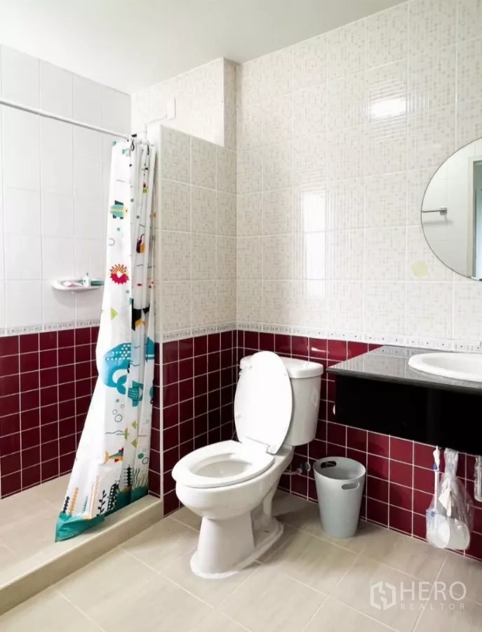 Detached House for rent or sale in Prawet, Bangkok - Family bathroom with red accent tiles, shower curtain and vanity.