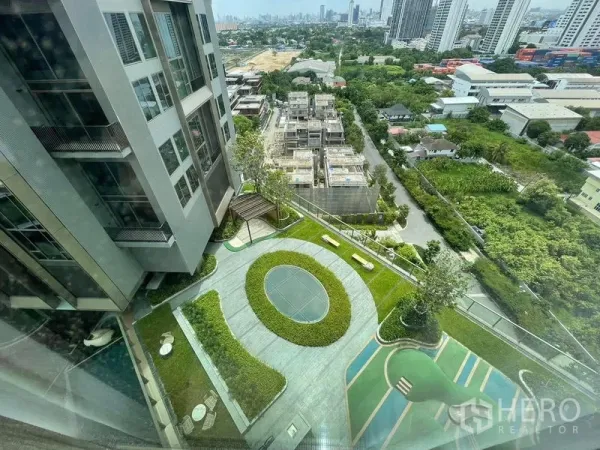 Condominium for rent in Samut Prakan - High-floor view over the condominium’s garden courtyard with walking paths and greenery.