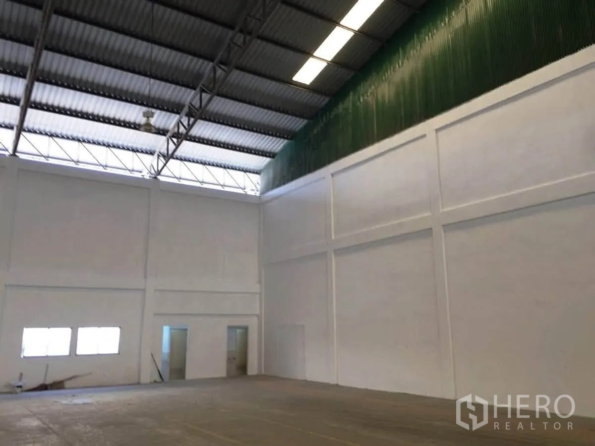 โกดัง for rent in Bang Sao Thong, Samut Prakan - มุมมองภายในเห็นผนังสูง แผ่นหลังคาโปร่งแสง และประตูทางคน