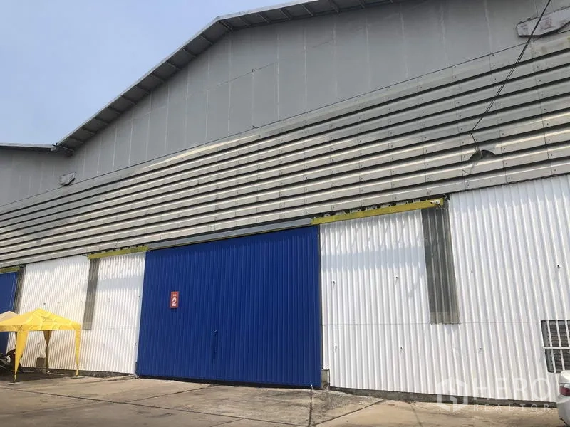 Warehouse for rent in Pak Kret, Nonthaburi - Metal-clad warehouse exterior with large blue sliding doors and a loading apron in Pak Kret, Nonthaburi