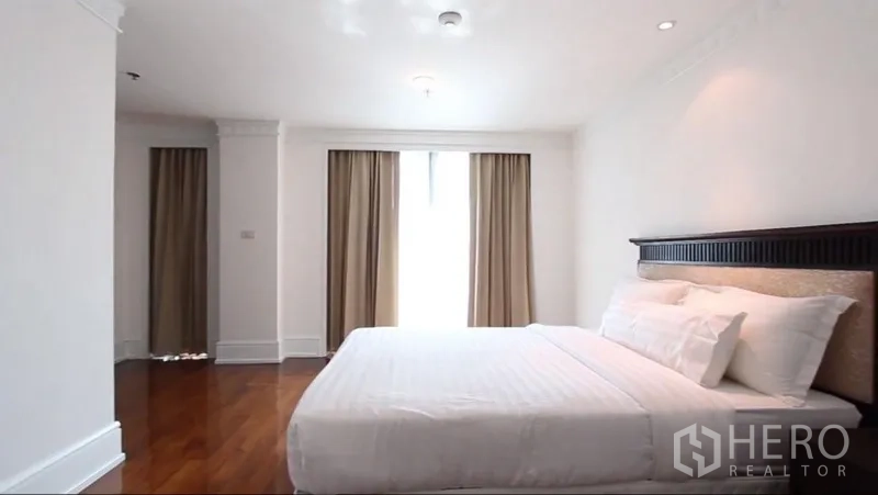 房间 出租在Khlong Toei, Bangkok - 明亮卧室，特大床，白色床品，木地板与带窗帘的落地窗。