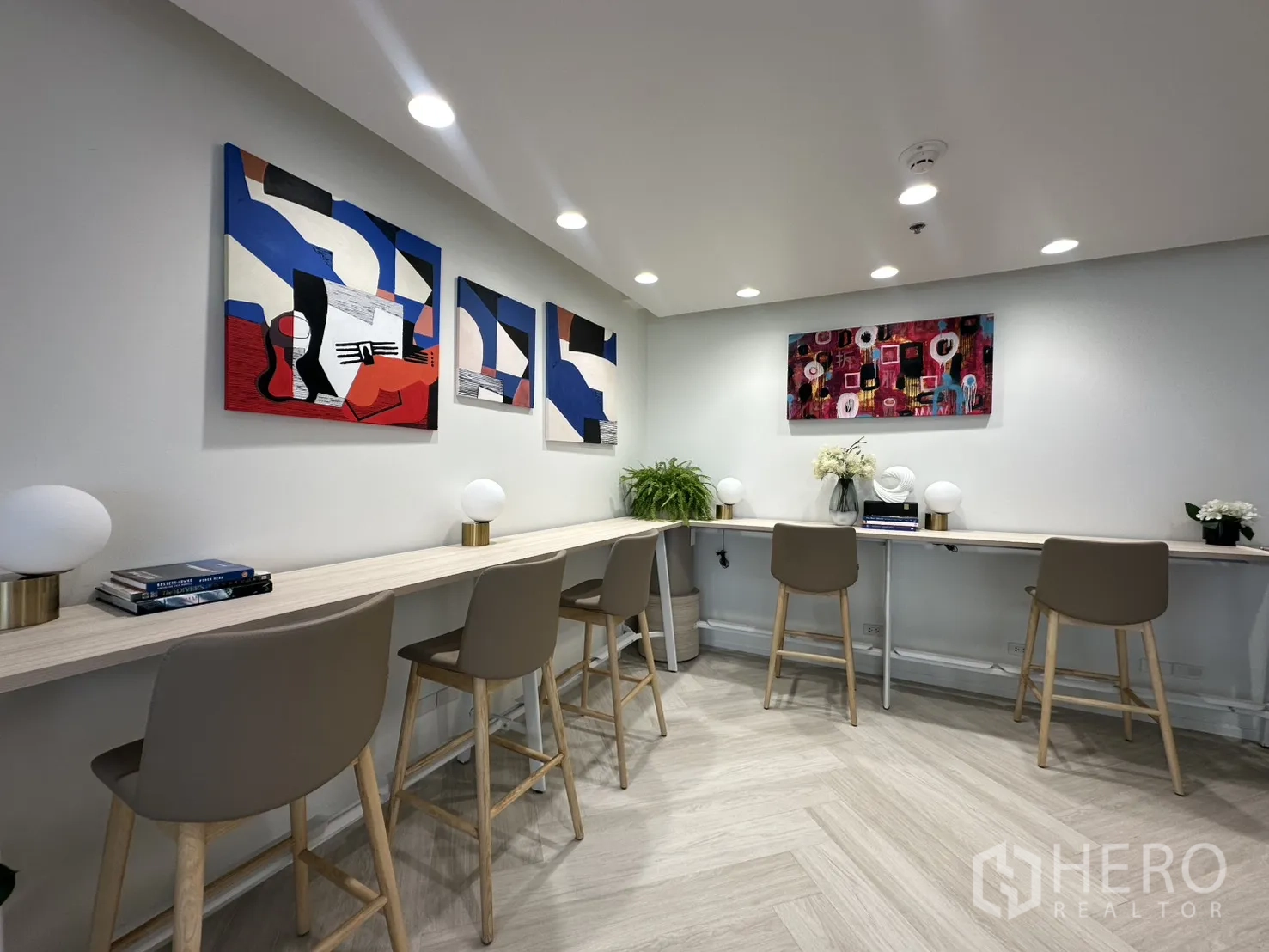 Office Space for rent in Sathon, Bangkok - Quiet work counter with bar stools, accent lamps, plants, and colorful abstract artwork on the wall.