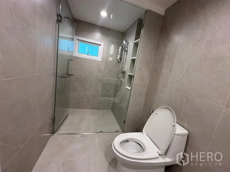 Home Office for rent in Khlong Toei, Bangkok - Bathroom with glass-enclosed rain shower and gray tiles.