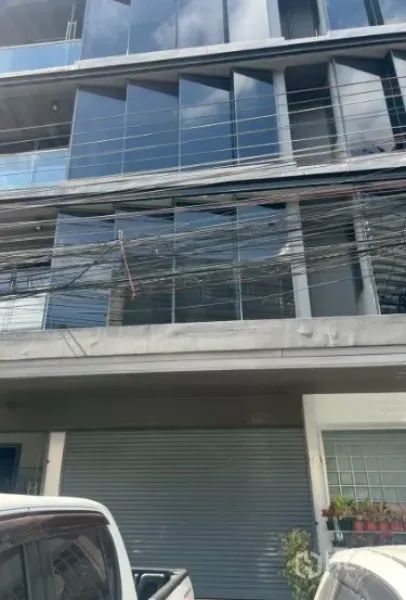 พื้นที่ขายปลีก ให้เช่าในKhlong Toei, Bangkok - อาคารภายนอกสมัยใหม่ กระจกสะท้อนแสง ราวระเบียง ประตูม้วนชั้นล่าง และรถจอดริมถนน