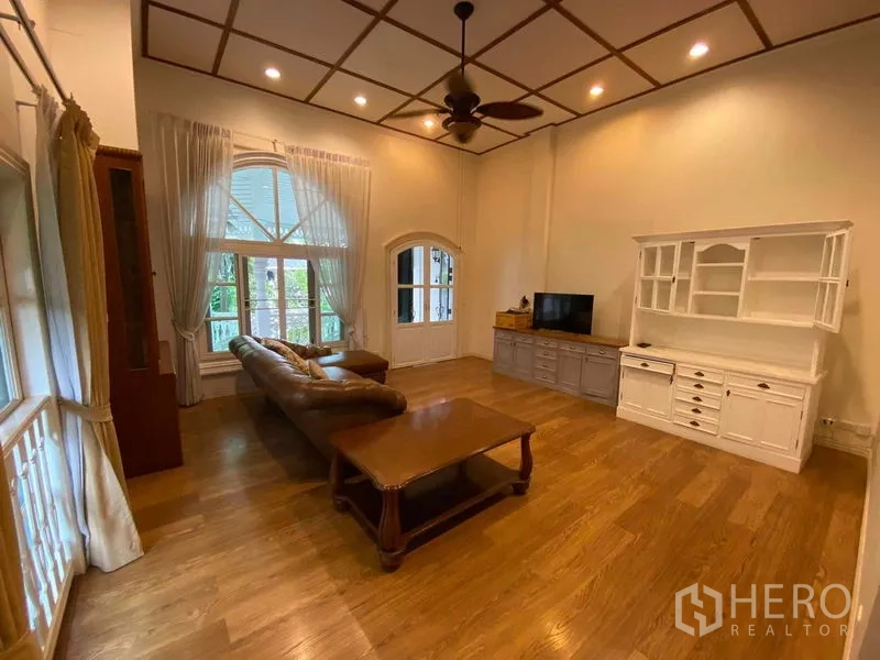 联排别墅 出租或出售在Mueang Samut Prakan, Samut Prakan - 客厅挑高拱窗，皮沙发与电视柜。