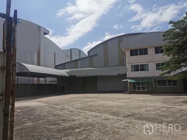 Factory for rent in Mueang Chachoengsao, Chachoengsao - Wide concrete yard in front of a high‑roof factory with attached office building in Chachoengsao.
