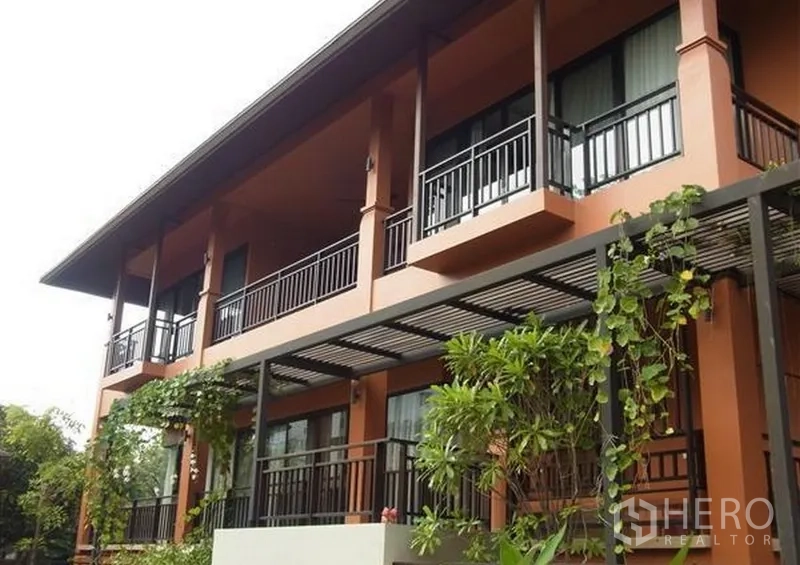 บ้าน ให้เช่าในKhlong Toei, Bangkok - ด้านหน้าอาคารบ้านสองชั้นสีเทอร์รากอตตา มีระเบียง เพอร์โกลา และไม้ประดับ