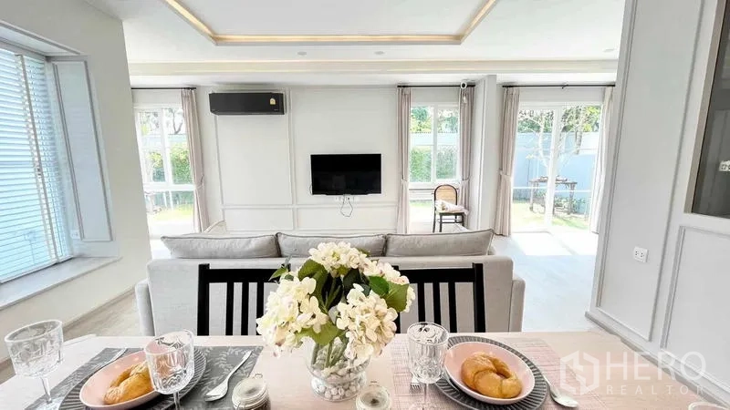 Detached House for rent or sale in Prawet, Bangkok - Dining table view toward sofa and sliding doors opening to the lawn.