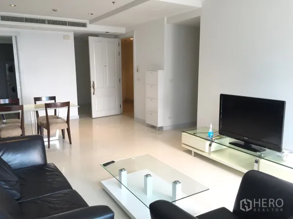 คอนโด ให้เช่าในPathum Wan, Bangkok - ห้องนั่งเล่นสว่าง โซฟาหนังสีดำ ชั้นวางทีวี และโต๊ะกลางกระจก