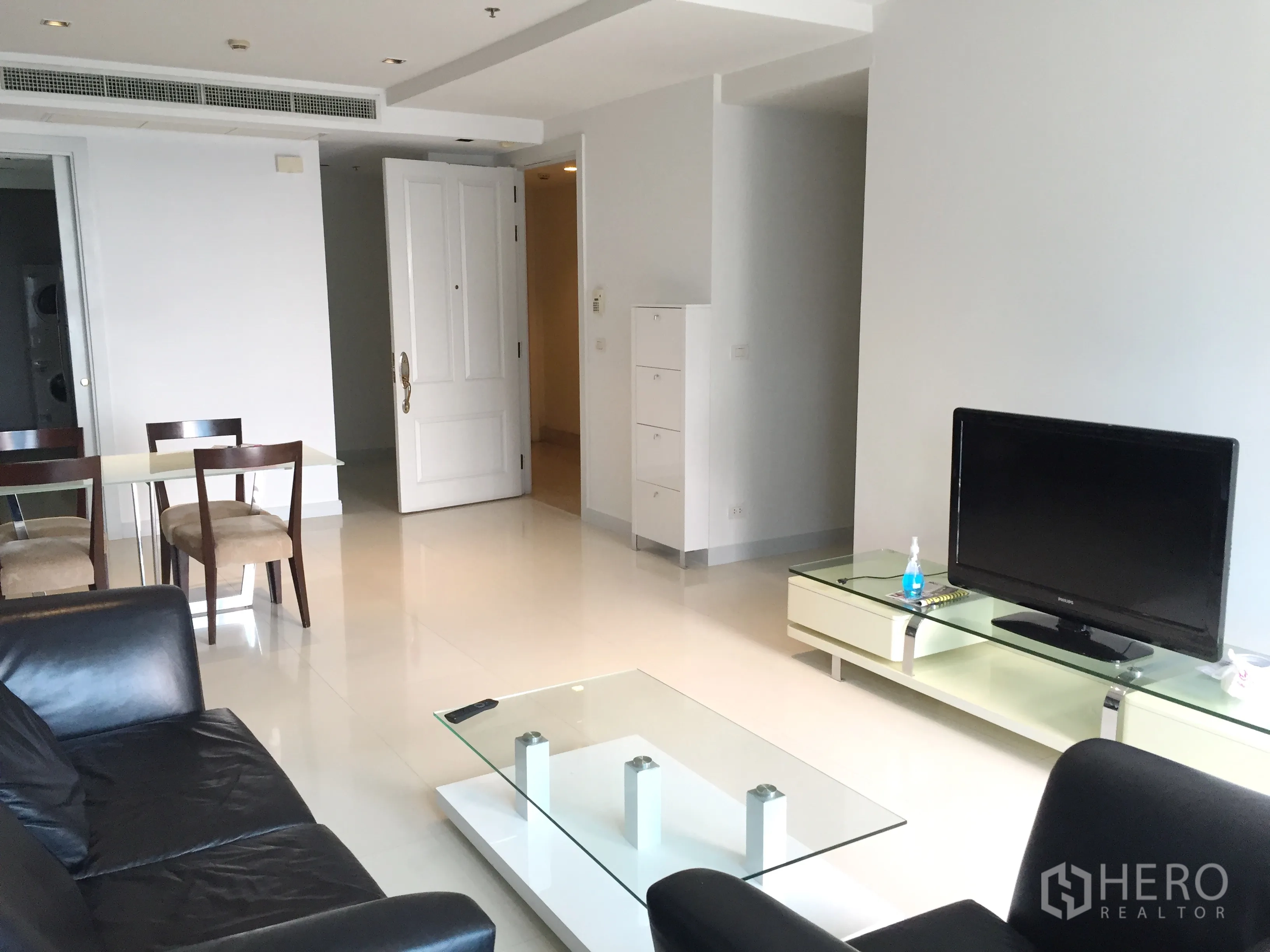 คอนโด ให้เช่าในPathum Wan, Bangkok - ห้องนั่งเล่นสว่าง โซฟาหนังสีดำ ชั้นวางทีวี และโต๊ะกลางกระจก