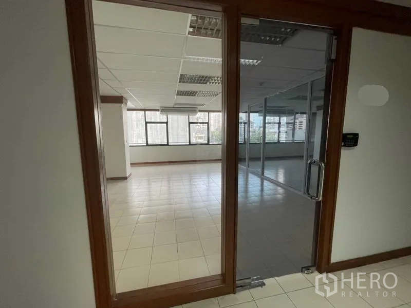 Office Space for rent in Khlong Toei, Bangkok - Glass door entry to an office with city-view windows and internal glass partitions.