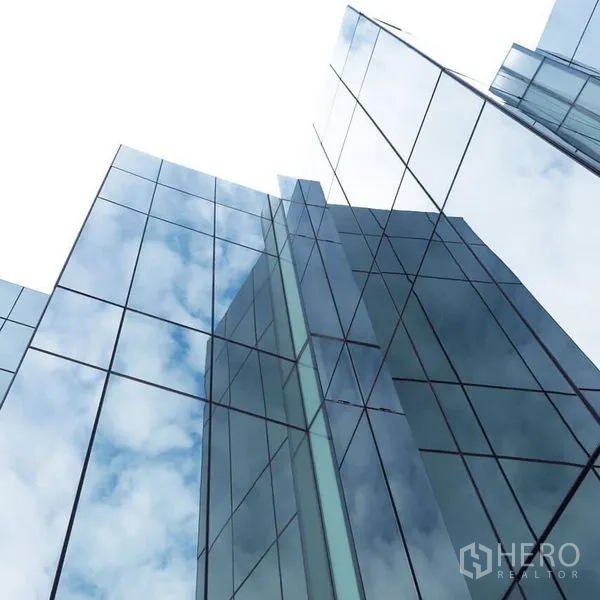 Office Space for rent in Khlong Toei, Bangkok - Reflective glass facade of a modern high-rise office tower against the sky.