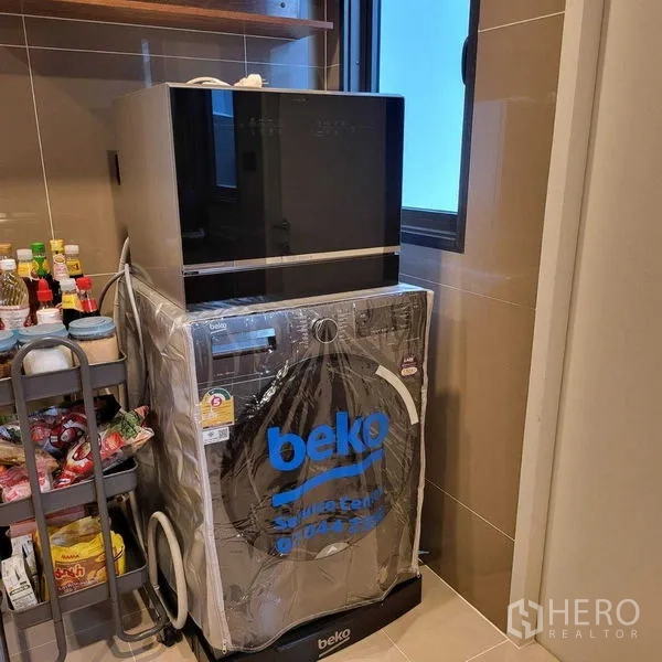 Detached House for rent in Mueang Pathum Thani, Pathum Thani - Laundry corner with stacked dishwasher and washing machine beside pantry cart