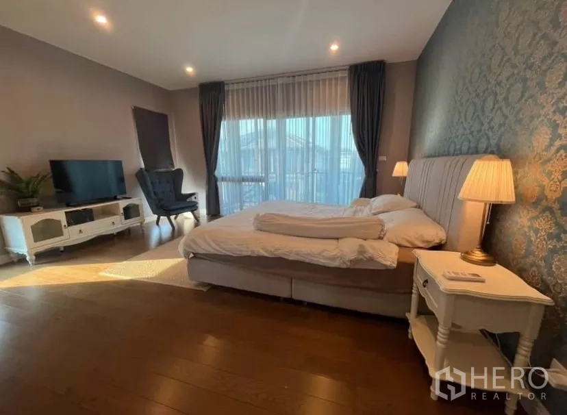 Detached House for rent in Prawet, Bangkok - Master bedroom with king bed, TV cabinet and full-height curtained windows.