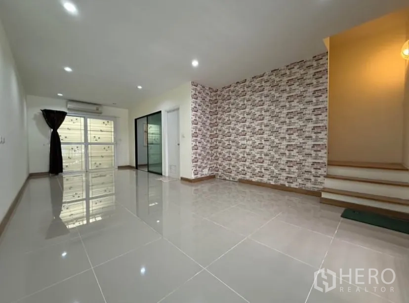 ทาวน์เฮาส์ ให้เช่าในSuan Luang, Bangkok - โถงรับแขกกว้าง ผนังตกแต่งลายอิฐ และบันไดขึ้นชั้นบน