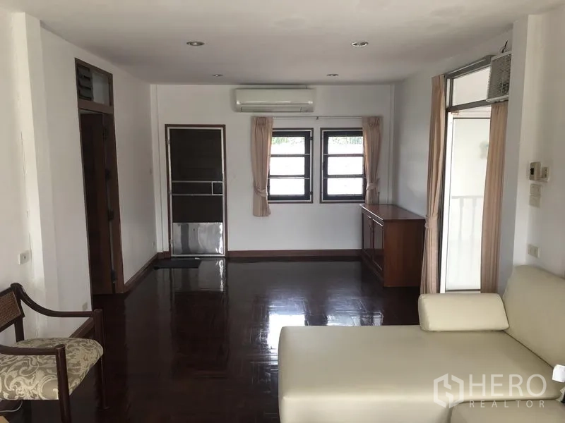 Detached House for rent in Khlong Toei, Bangkok - Upper family room with glossy wood floors, air-conditioning and balcony door.