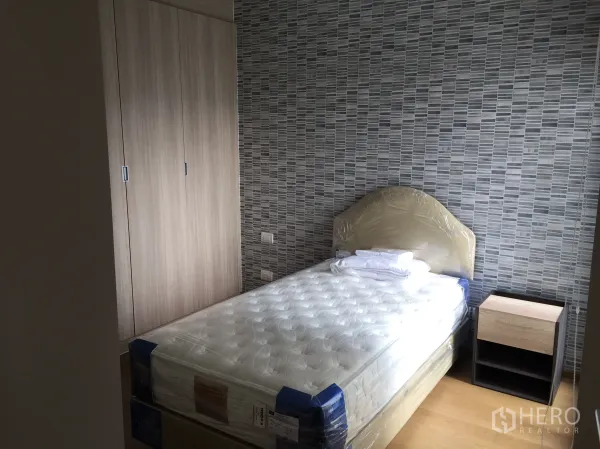 คอนโด ให้เช่าในPathum Wan, Bangkok - ห้องนอนขนาดกะทัดรัด เตียงเดี่ยว ตู้เสื้อผ้าบิวท์อิน และผนังลายกราฟิก