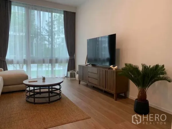 บ้าน ให้เช่าในSaphan Sung, Bangkok - มุมนั่งเล่นอบอุ่น มีตู้วางทีวี โต๊ะกาแฟกลม ผ้าม่านสูง และวิวสวน