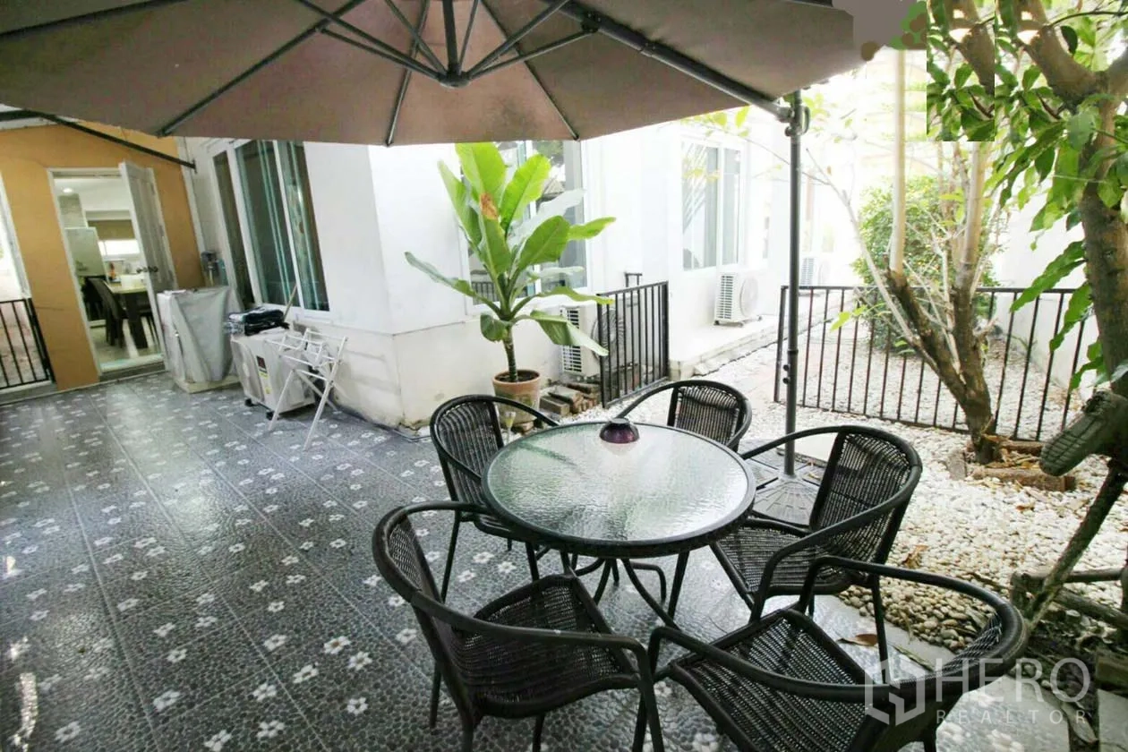 บ้าน ให้เช่าหรือขายในLat Krabang, Bangkok - ลานระเบียงกลางแจ้งมีร่ม โต๊ะกลมกระจก เก้าอี้หวาย และกระถางต้นไม้