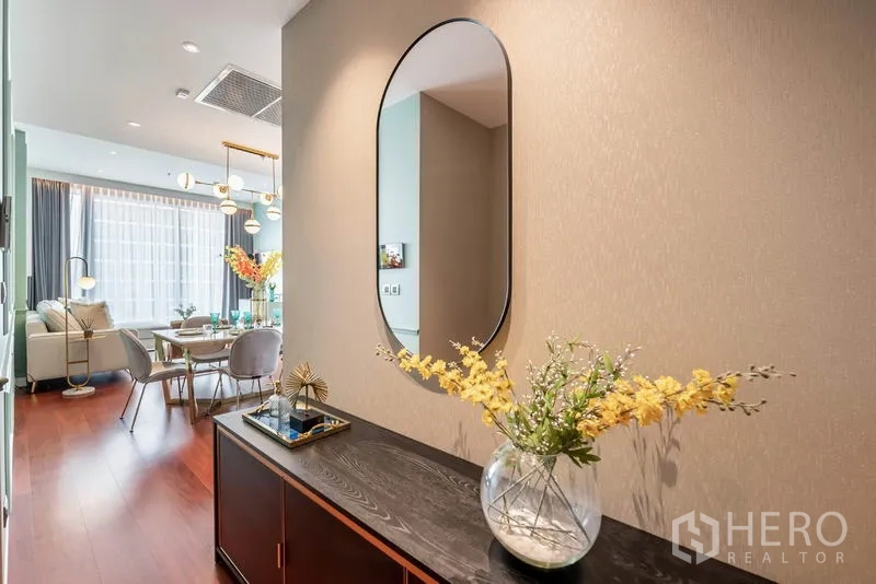 公寓 出租或出售在Watthana, Bangkok - 入口走廊设椭圆镜与深色边柜，通往客餐厅。