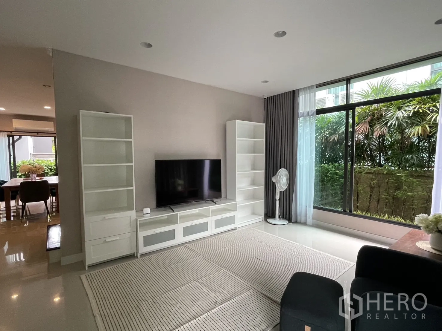 Detached House for rent in Bang Kapi, Bangkok - Bright living room with large window, TV console and white shelving.
