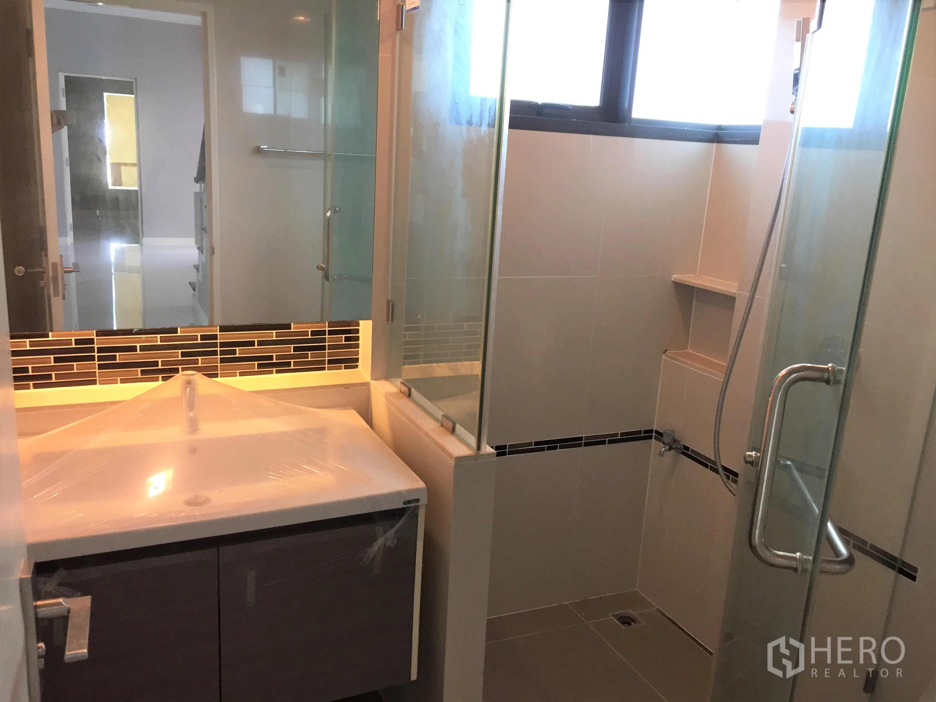 Detached House for rent or sale in Bang Kapi, Bangkok - Contemporary bathroom with glass shower enclosure and vanity.