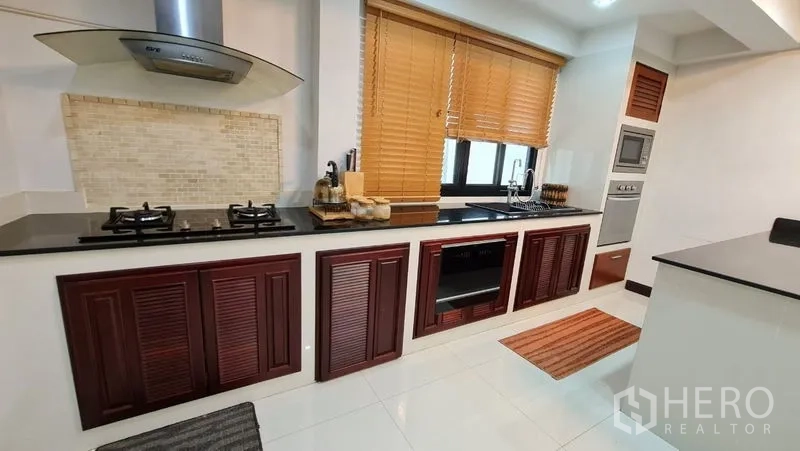 Detached House for rent in Saphan Sung, Bangkok - Kitchen cabinetry with granite countertops, built-in oven, and window blinds.