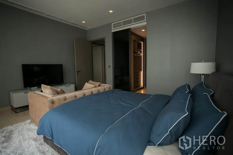 Condominium for rent or sale in Watthana, Bangkok - Second bedroom with blue bedding, TV unit and entry to walk-in closet.