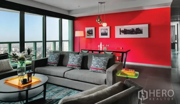 อพาร์ทเมนท์ ให้เช่าในKhlong San, Bangkok - พื้นที่นั่งเล่นและรับประทานอาหารแบบเปิดโล่ง กระจกพาโนรามา โซฟาสีเทา และผนังจุดเด่นสีแดง