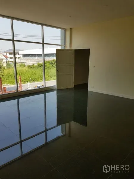 Factory for rent or sale in Mueang Samut Prakan, Samut Prakan - Large office room with floor-to-ceiling windows overlooking greenery and the road.