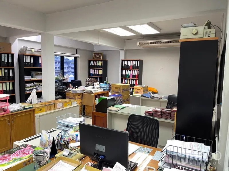 Office Space for rent in Khlong Toei, Bangkok - Workstations and filing cabinets in a windowed office with bright ceiling lights.