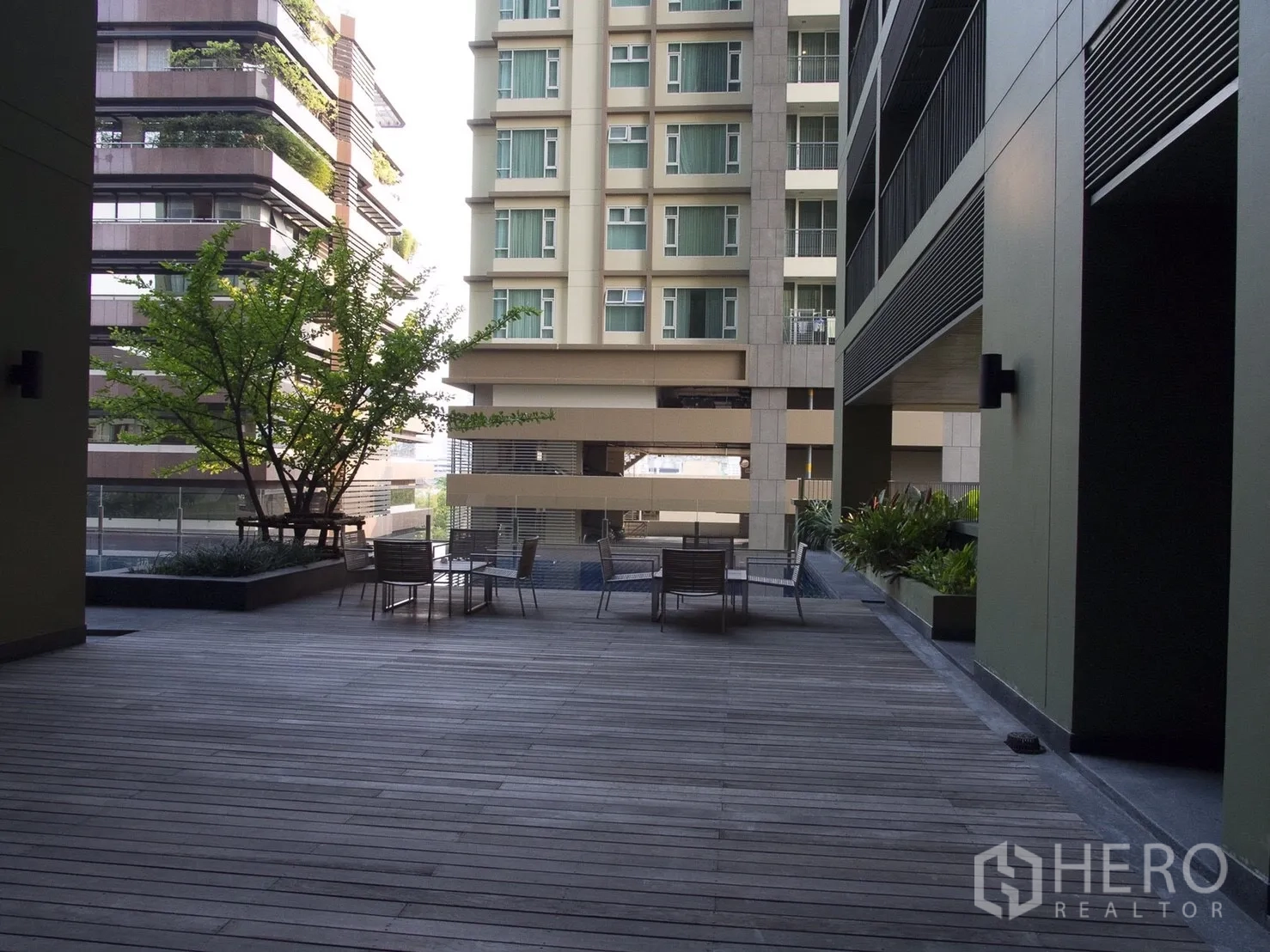 Condominium for rent or sale in Watthana, Bangkok - Shaded courtyard terrace between residential buildings with outdoor seating.
