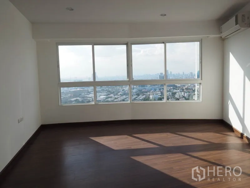 Condominium for rent in Yan Nawa, Bangkok - Corner bedroom with wide wraparound windows, wood floors and expansive city views.