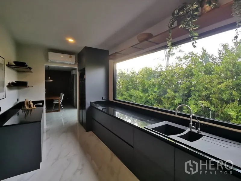Townhouse for rent in Bang Phli, Samut Prakan - Galley kitchen with long picture window over garden, black countertops and double sink.