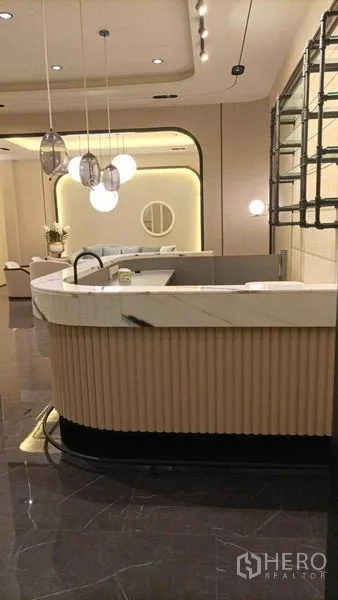 零售空间 出租 - 弧形大理石台面的接待台，搭配吊灯与展示架。