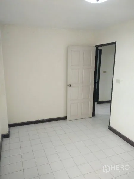 Townhouse for rent in Phra Khanong, Bangkok - Small interior room with white tiled floor, cream walls and an open panel door.