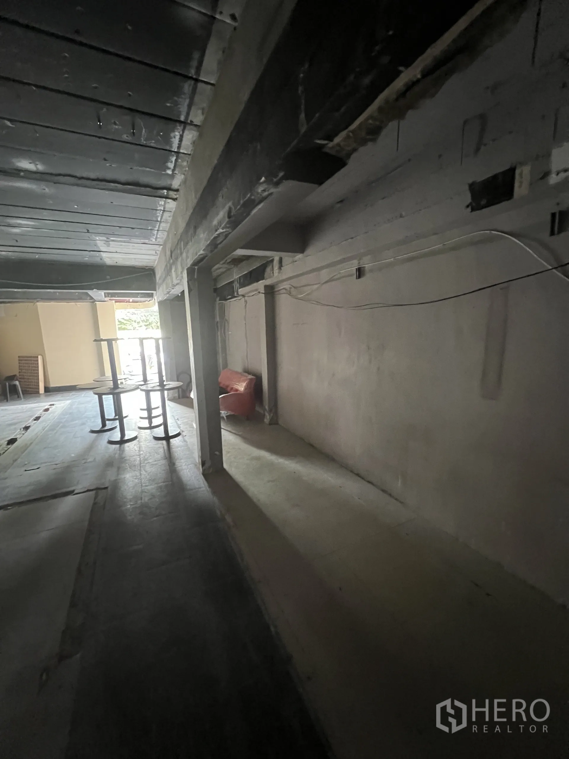 零售空间 出租在Watthana, Bangkok - 店内侧向通道，见结构梁与电线，朝向前部开口采光。