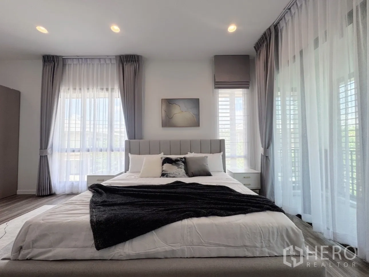 บ้าน ให้เช่าหรือขายในBang Kapi, Bangkok - มุมใกล้เตียงหุ้มผ้าในโทนสีเทาอ่อน พร้อมม่านโปร่ง