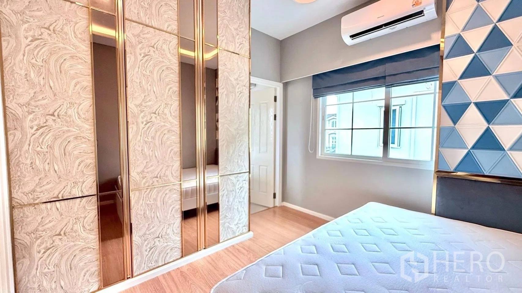 Detached House for rent or sale in Bueng Kum, Bangkok - Bedroom with patterned wardrobe, blue geometric accent wall, air conditioner and window.
