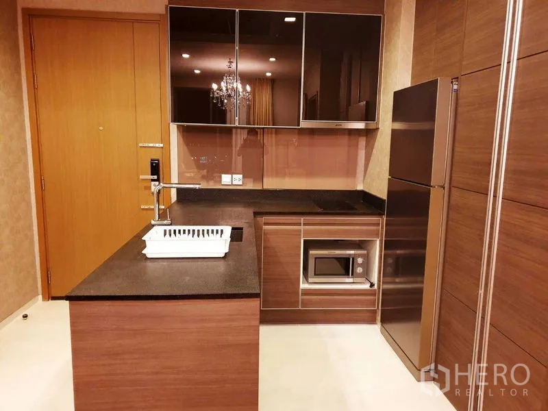 公寓 出租或出售在Khlong Toei, Bangkok - 现代厨房，木纹橱柜、石面台、中岛水槽、嵌入式微波炉与不锈钢冰箱。
