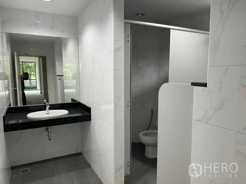 办公空间 出租在Bang Rak, Bangkok - 新铺面的卫生间，带大镜子、黑色台面洗手池和隔间马桶。